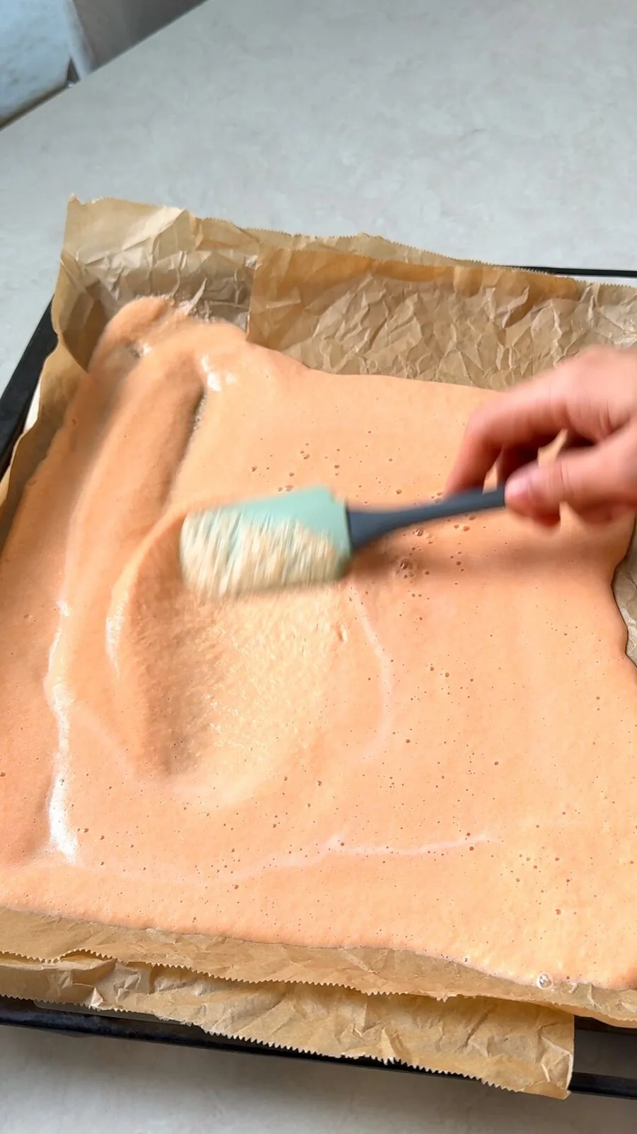 Red lentil batter brushed into a thin layer on a tray