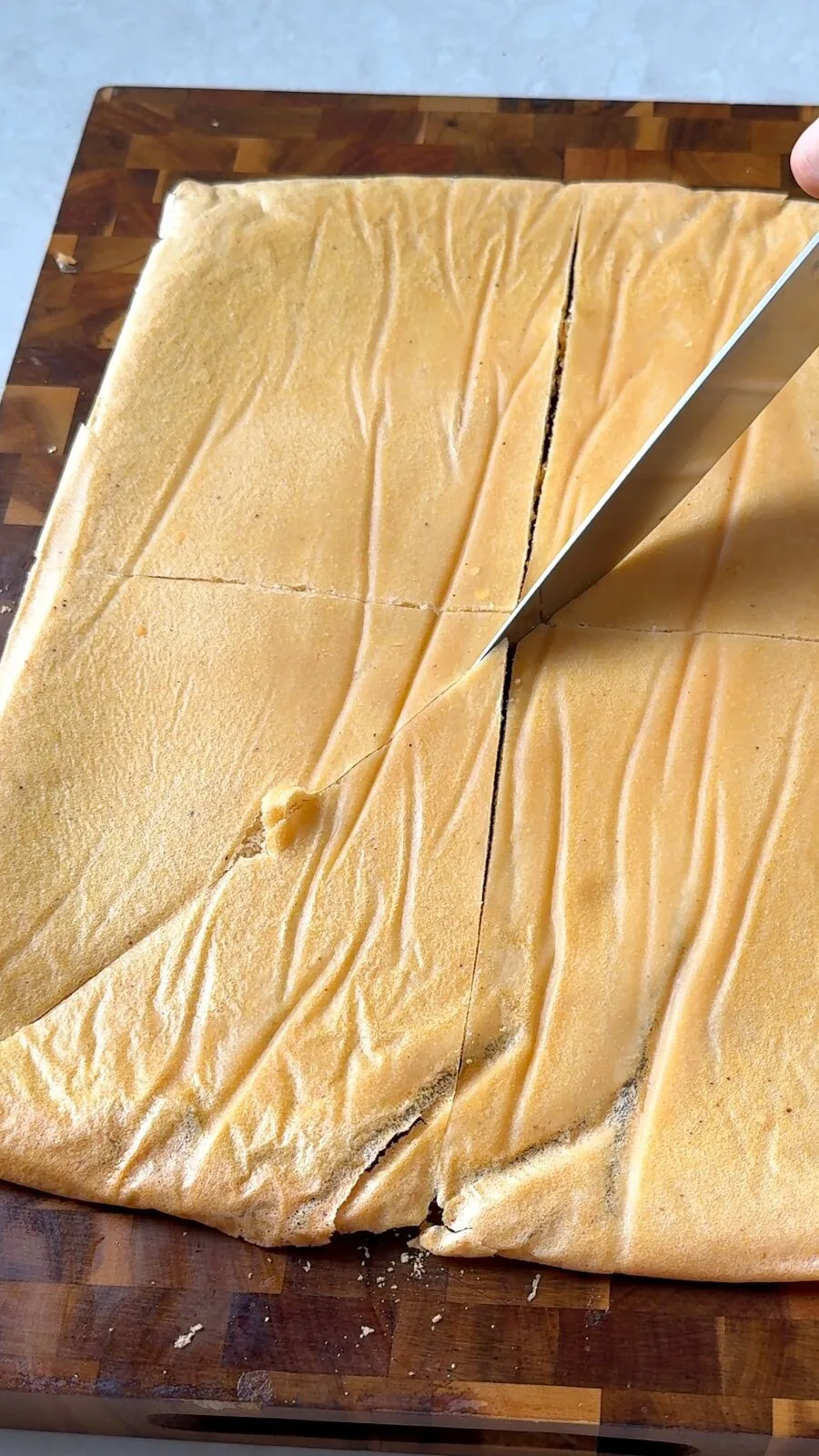 Baked lentil sheet being cut into triangle chips