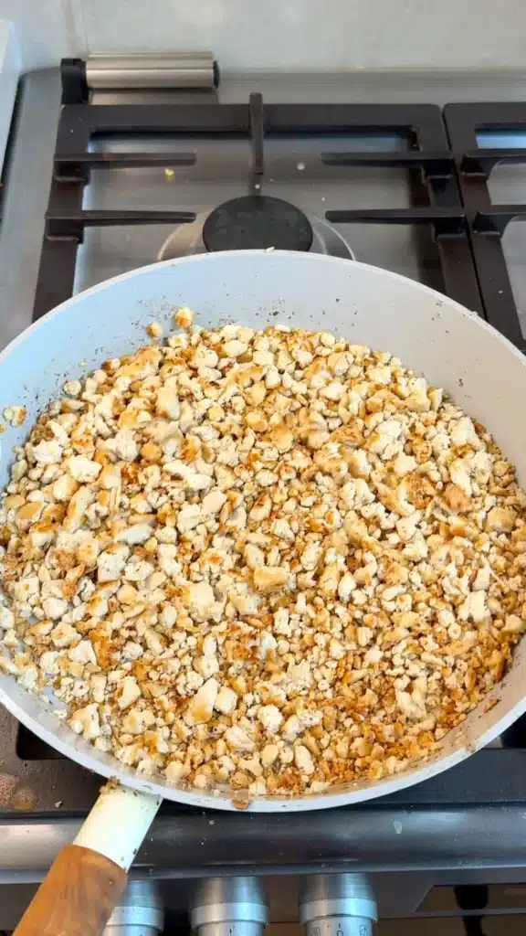 Crumbled tofu beginning to brown in a frying pan