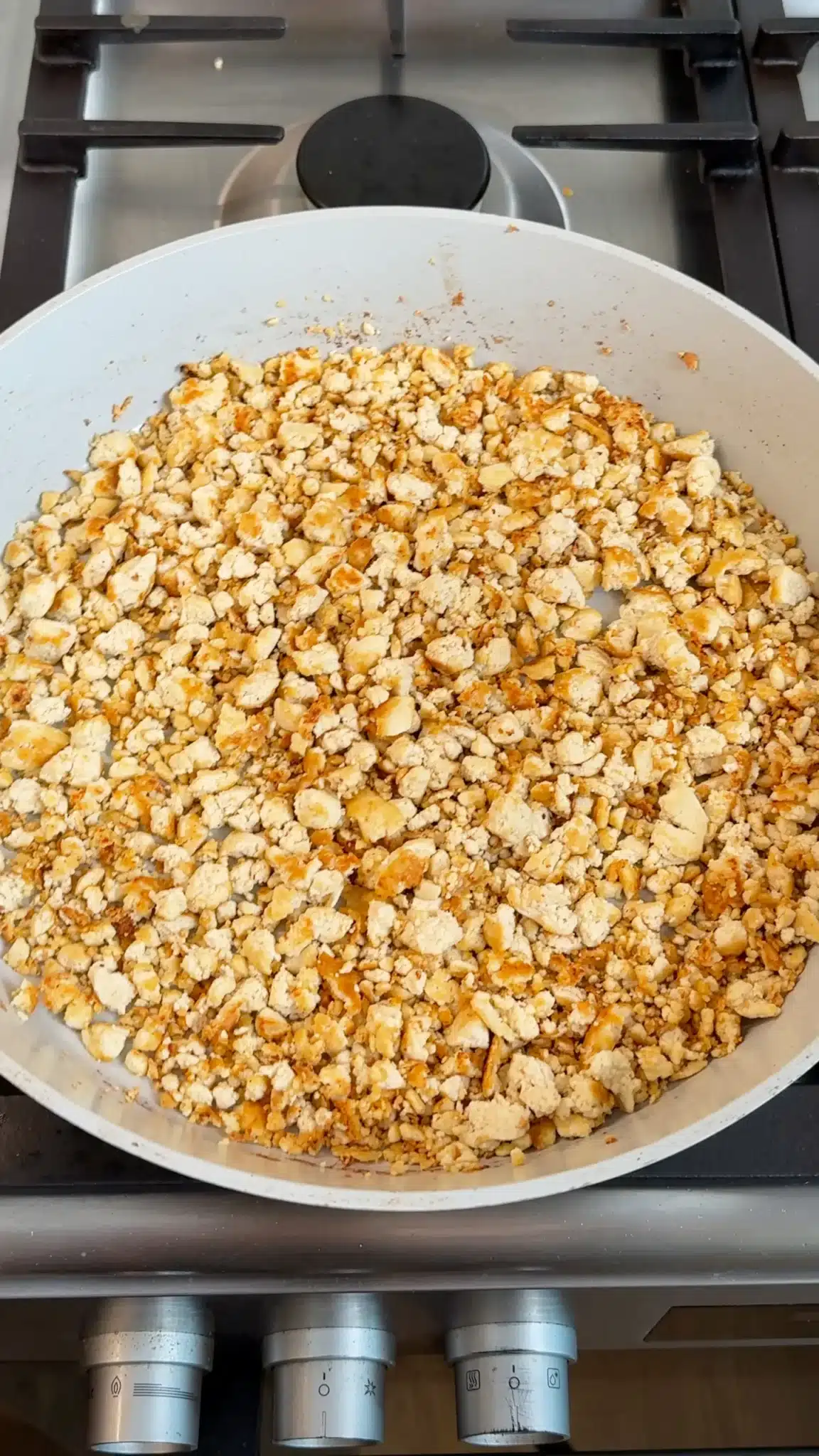 Crumbled tofu with golden patches in a wide skillet