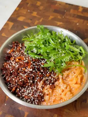 Creamy udon noodles topped with dark glazed tofu crumbles, scallions, cilantro and sesame seeds