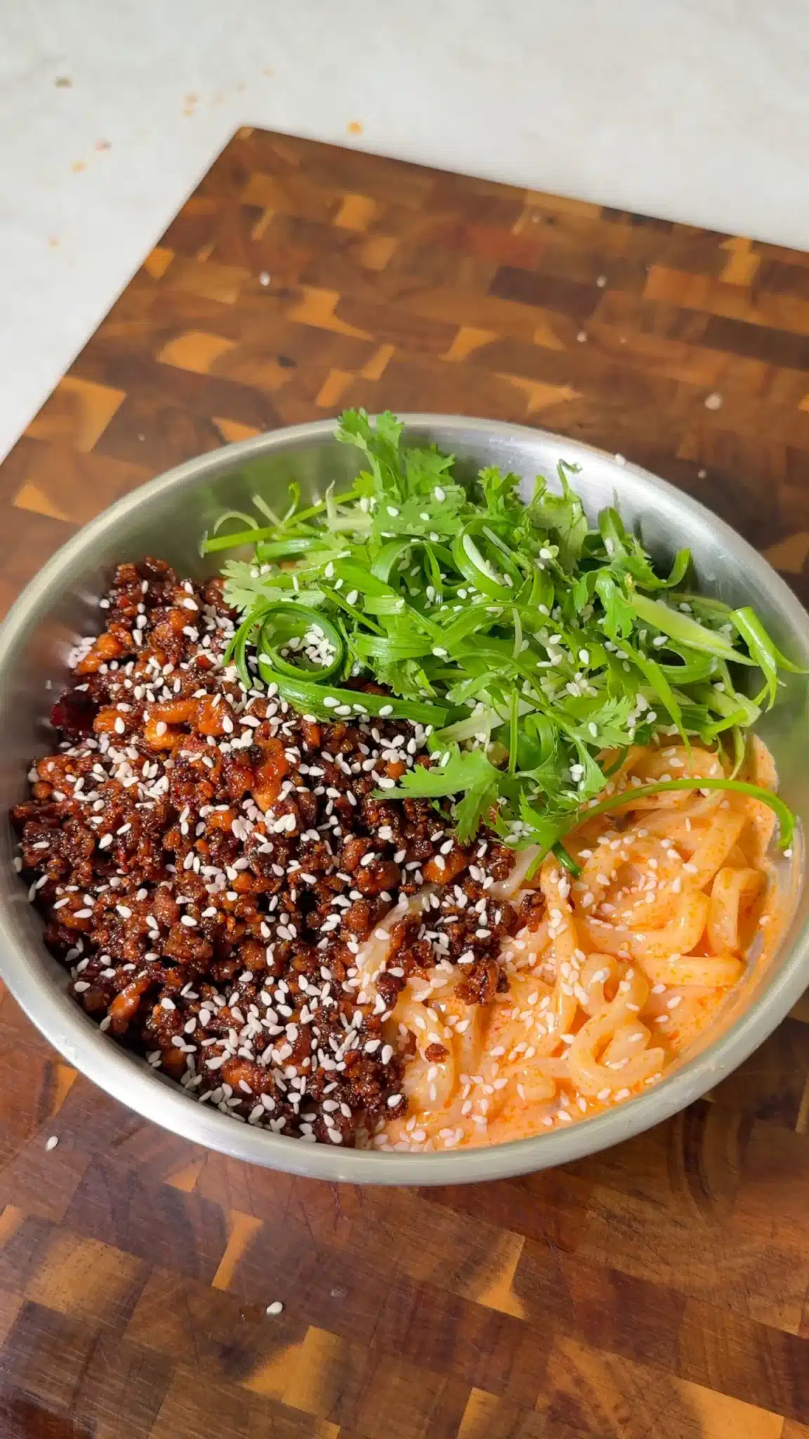 Creamy udon noodles topped with dark glazed tofu crumbles, scallions, cilantro and sesame seeds