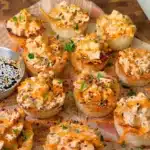 Crispy rice sushi cups filled with spicy tofu, sriracha mayo, sesame seeds and herbs on a board with soy sauce