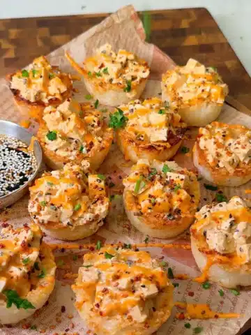 Crispy rice sushi cups filled with spicy tofu, sriracha mayo, sesame seeds and herbs on a board with soy sauce