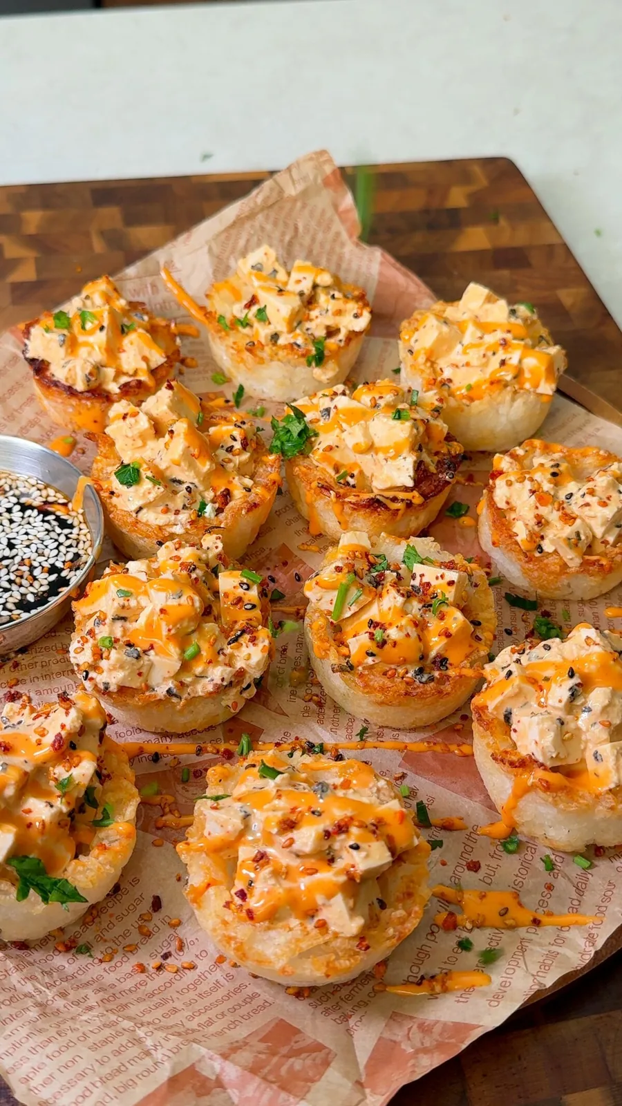 Crispy rice sushi cups filled with spicy tofu, sriracha mayo, sesame seeds and herbs on a board with soy sauce