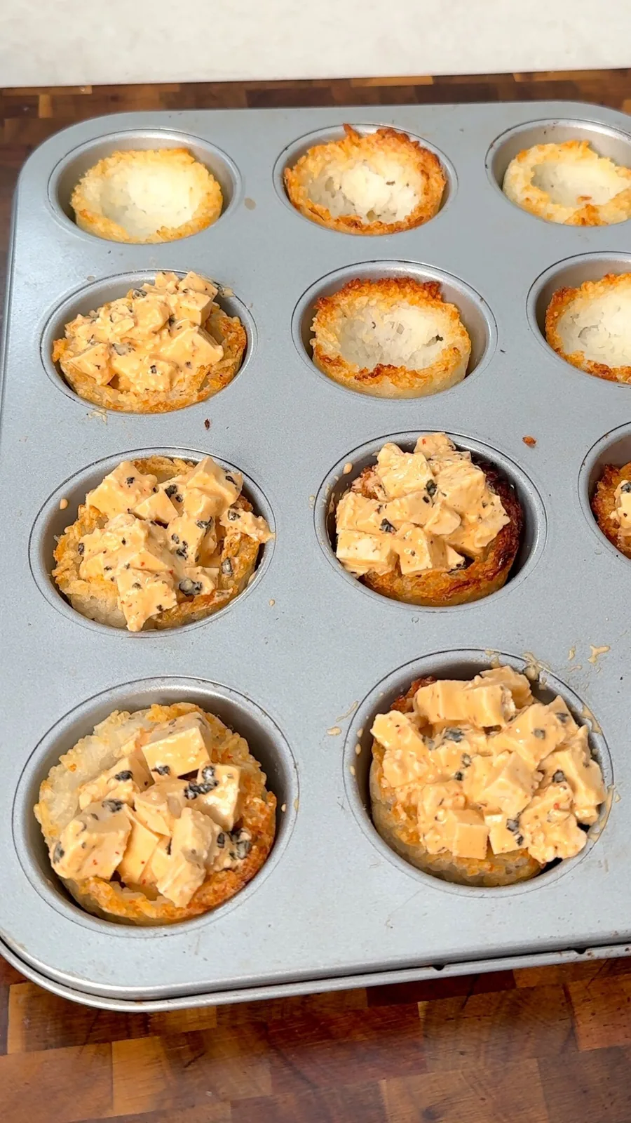Crispy rice cups being filled with spicy tofu in the muffin tin