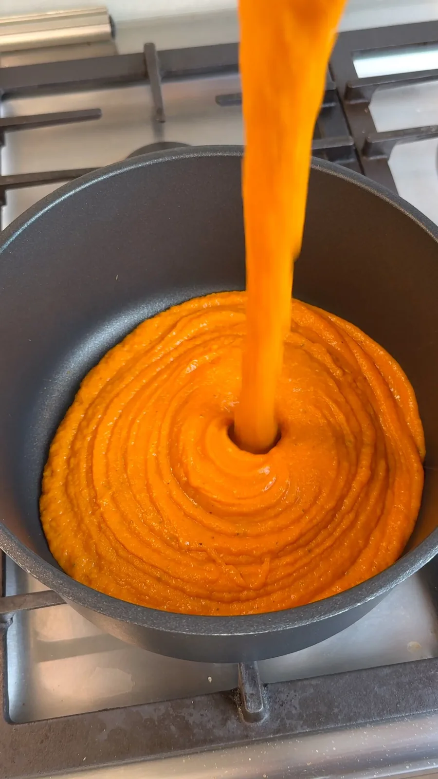 Thick blended roasted butternut squash soup being poured into a pot
