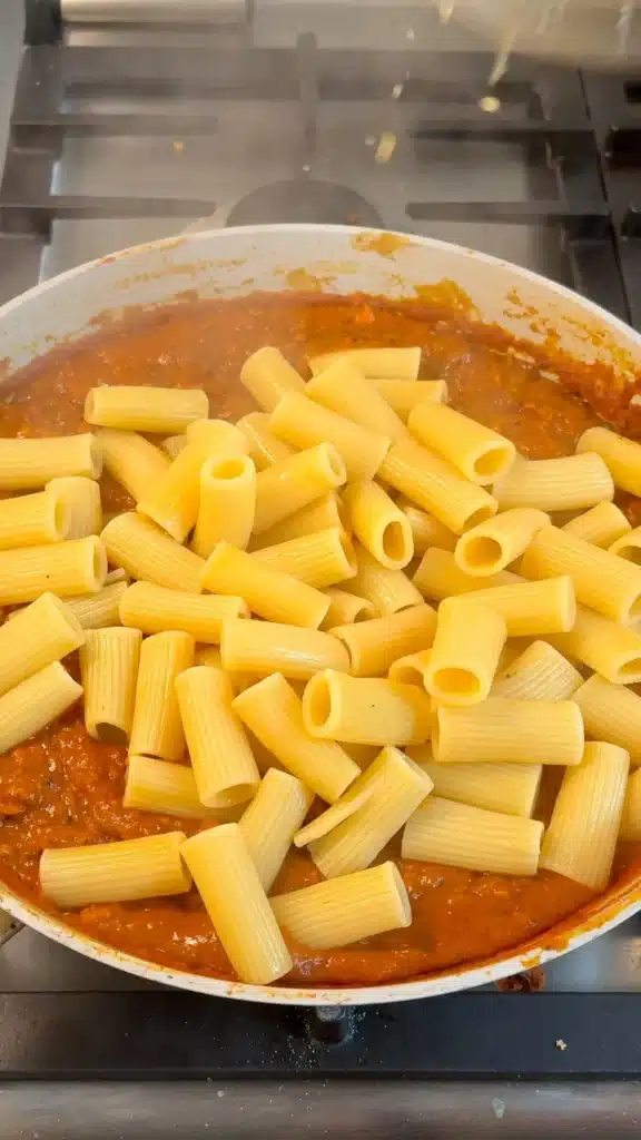 Cooked rigatoni added to the roasted red pepper pasta sauce and tofu crumbles before tossing