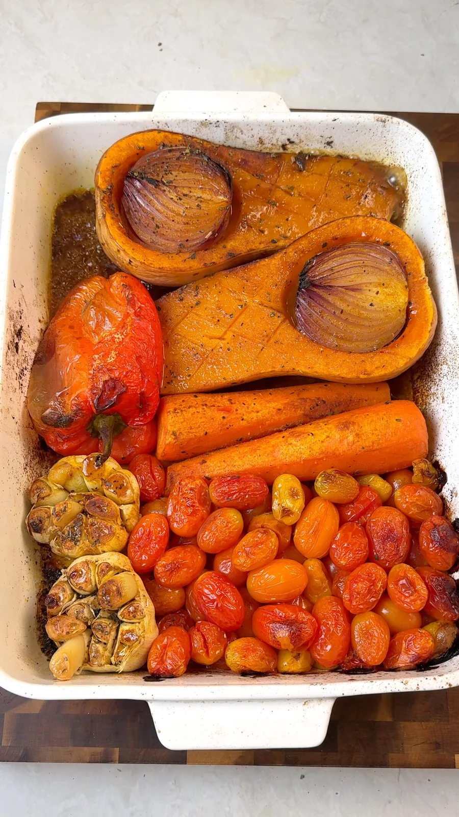 Caramelized roasted butternut squash, garlic, peppers and burst cherry tomatoes in a roasting dish