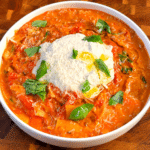 Creamy lasagna soup topped with vegan parmesan, cream cheese, basil, and olive oil