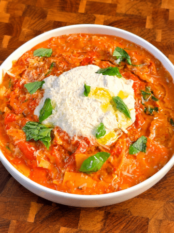 Creamy lasagna soup topped with vegan parmesan, cream cheese, basil, and olive oil