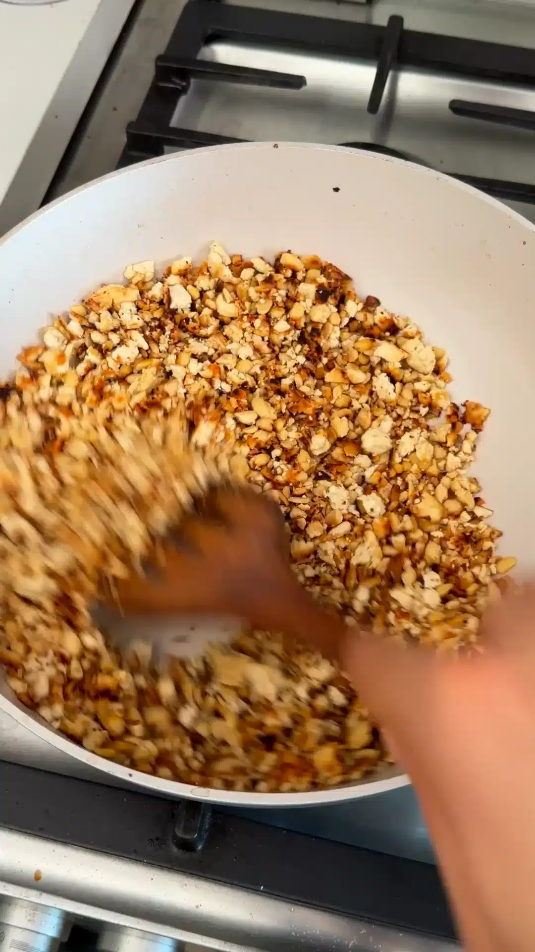 Crumbled tofu browning in olive oil in a frying pan.