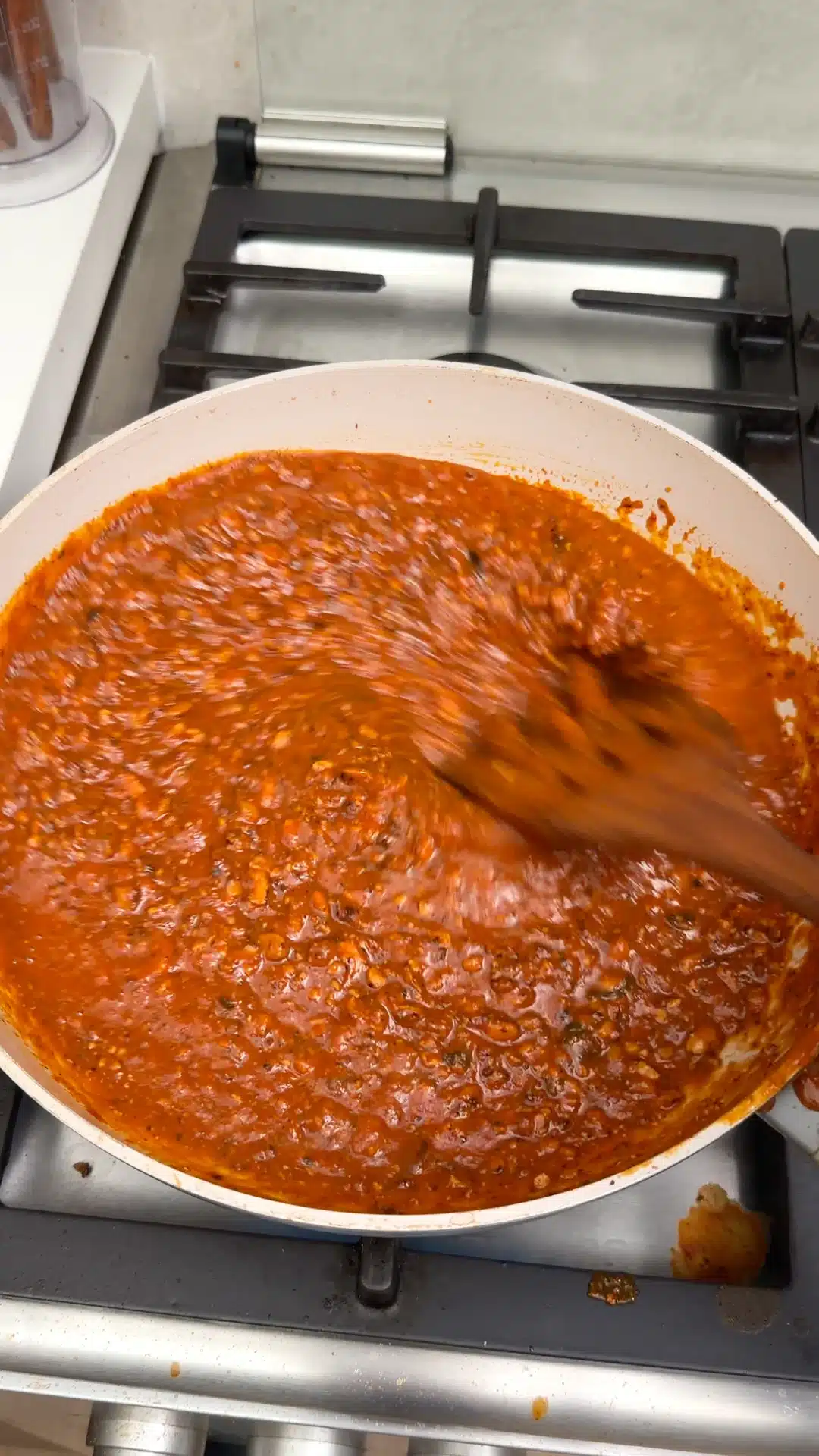 Tofu Bolognese being stirred in a white frying pan.