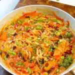Udon noodles in coconut curry sauce with vegetables, sesame and sliced spring onions