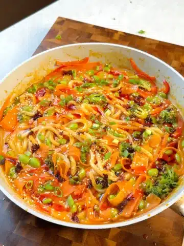 Udon noodles in coconut curry sauce with vegetables, sesame and sliced spring onions