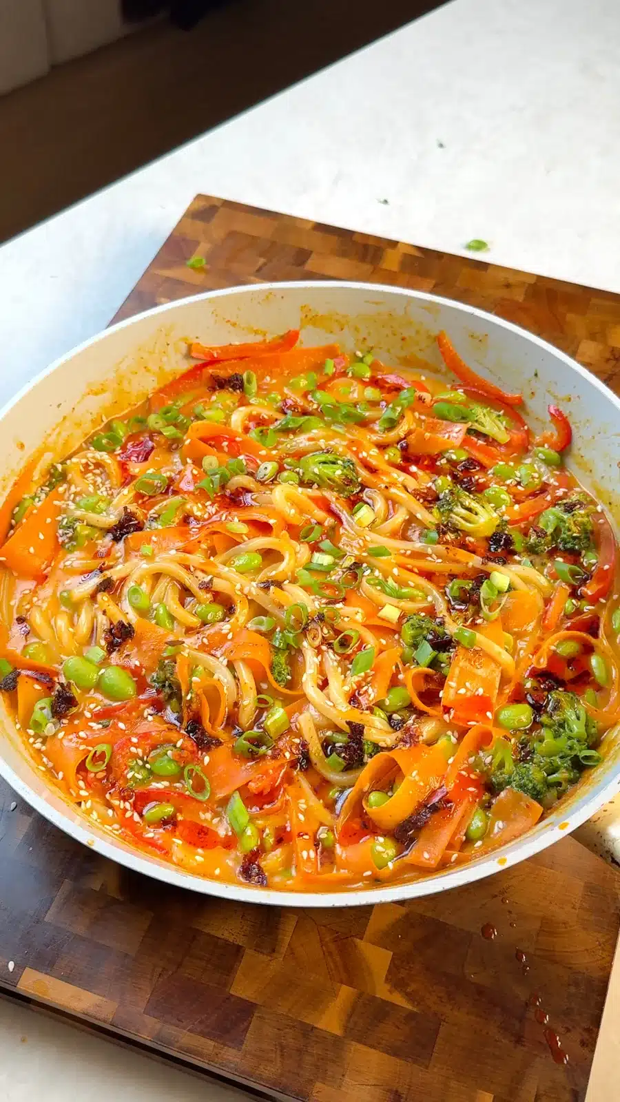 Udon noodles in coconut curry sauce with vegetables, sesame and sliced spring onions