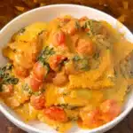 Creamy vegan ravioli with cherry tomatoes and spinach in a white bowl