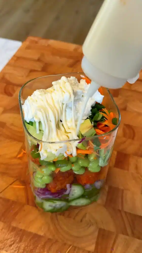 Cucumber, tofu, edamame and vegetables layered with creamy dressing in a jar