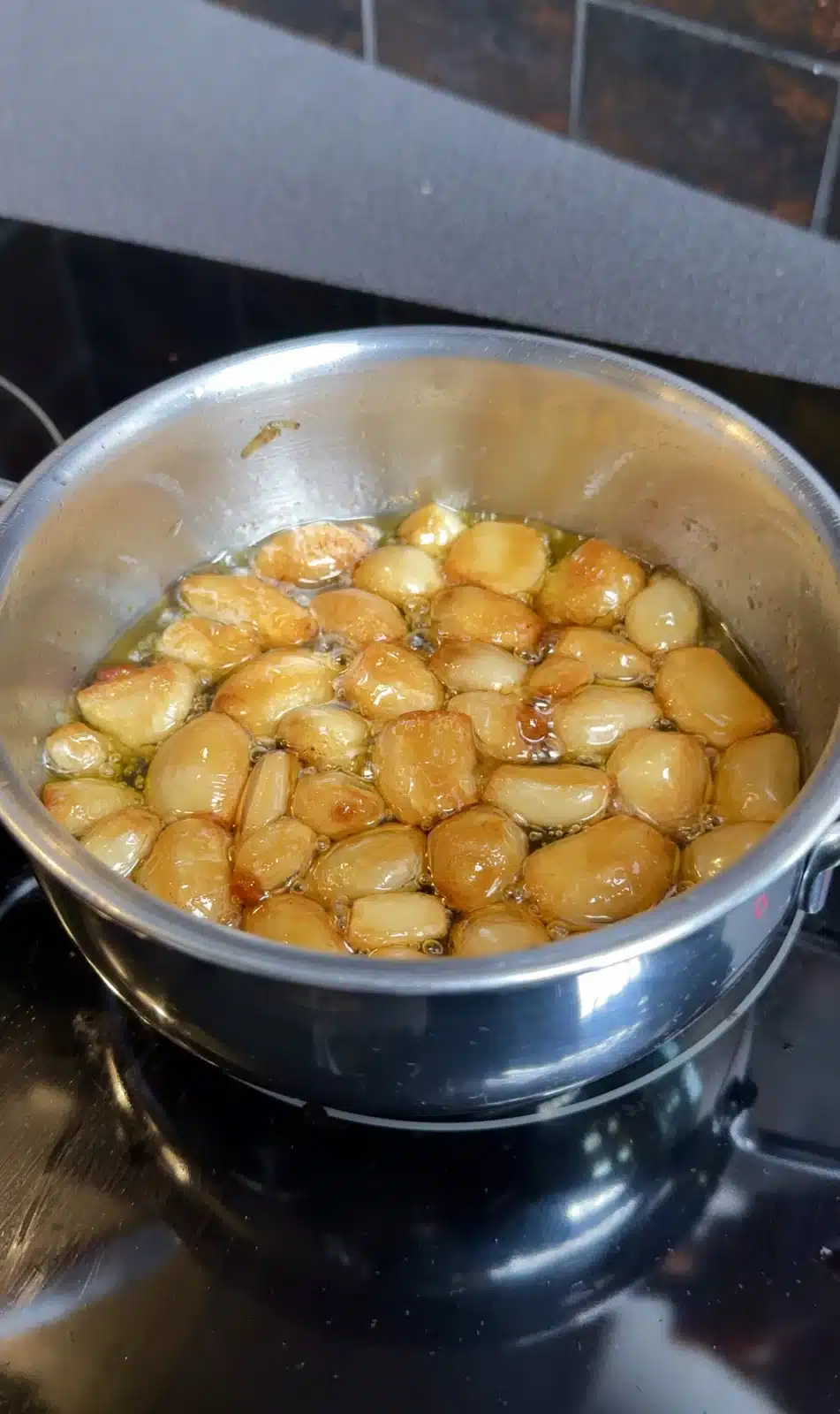 Peeled garlic cloves gently cooking in olive oil