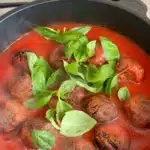Baked lentil meatballs in marinara sauce with fresh basil