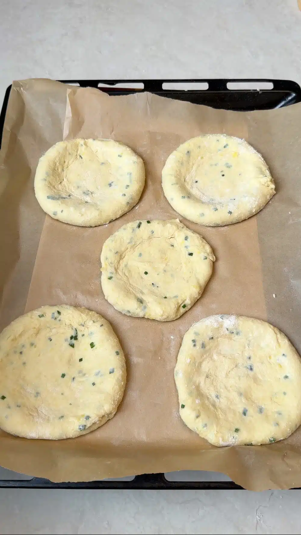 Five potato flatbreads with shallow centers on a baking tray