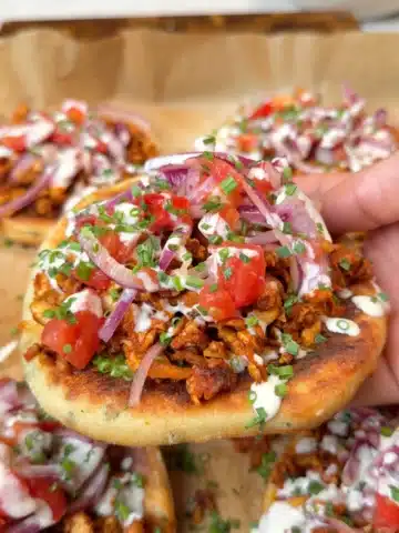 Baked potato flatbread topped with glazed tofu, tomato-onion salad, tahini yogurt and chives
