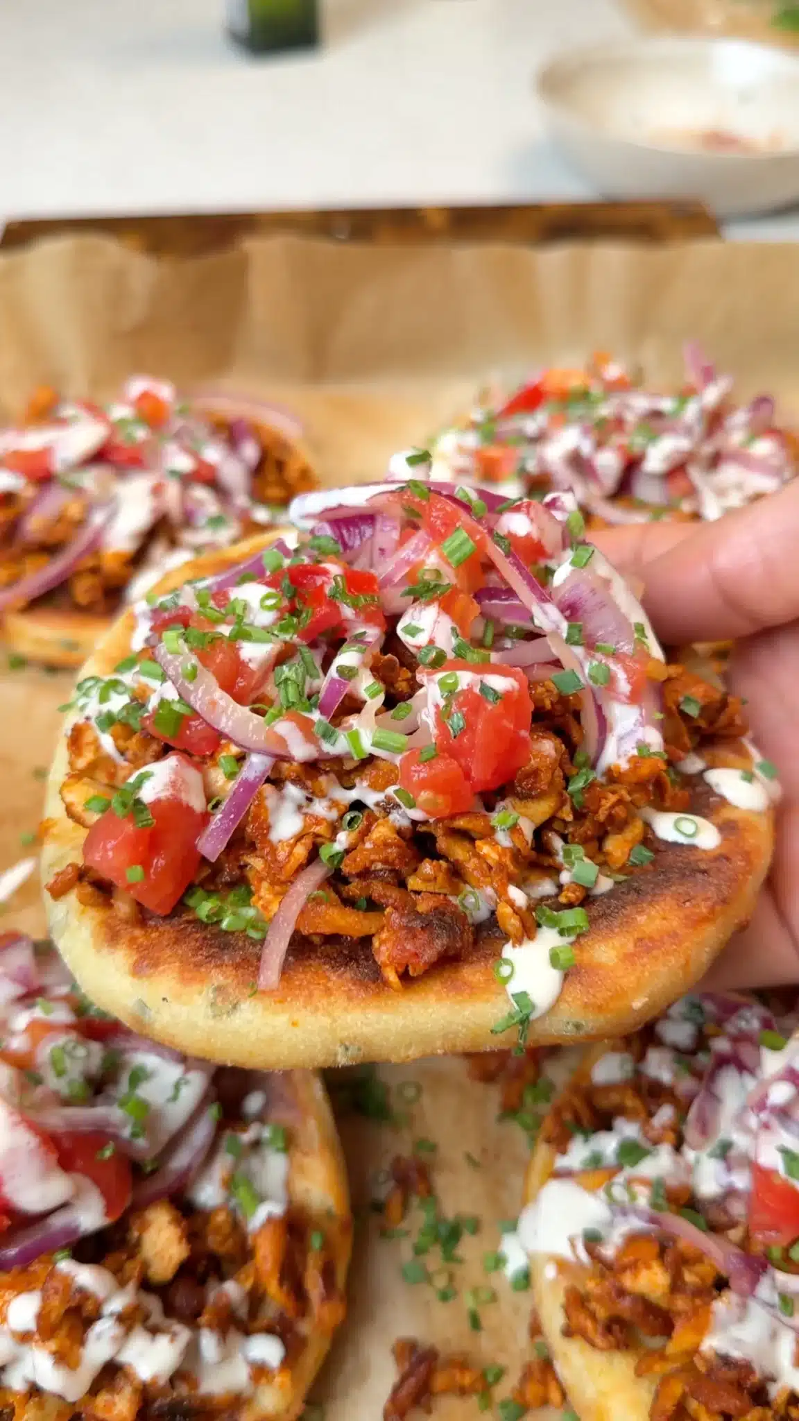 Baked potato flatbread topped with glazed tofu, tomato-onion salad, tahini yogurt and chives
