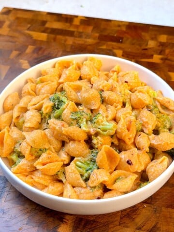 Vegan mac and cheese with broccoli and pasta shells in a white bowl
