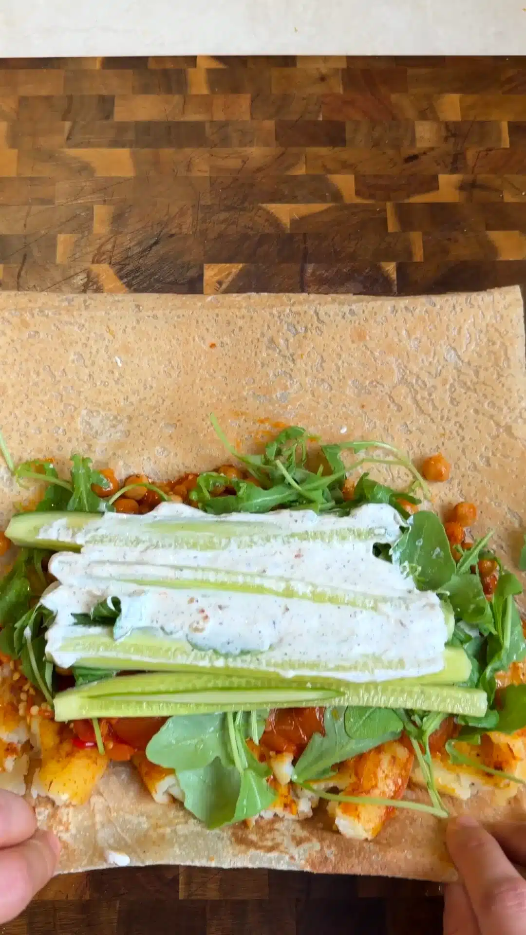 A lavash wrap topped with roasted vegetables, rocket, cucumber sticks and creamy garlic yogurt sauce.
